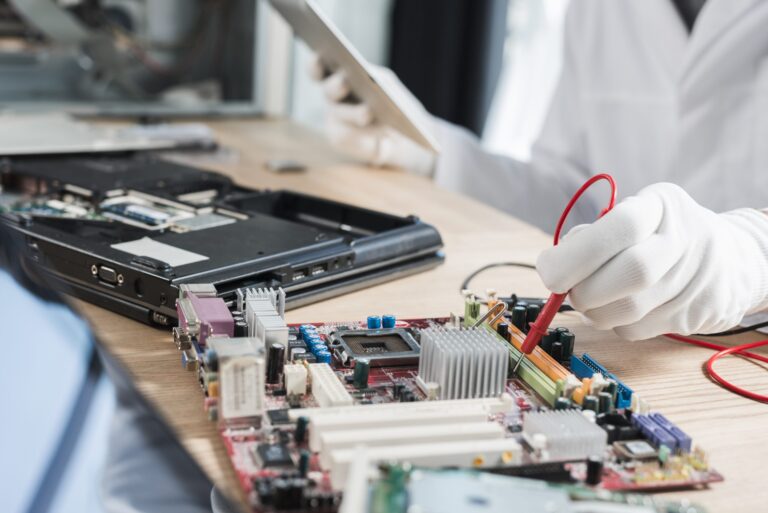 male technician examining mother board with digital multimeter scaled 1